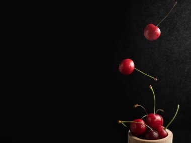 Koyu arkaplanda taze kirazlı dondurma aksiyon, sıçrama, su damlaları ve bokeh ile dinamik çekim. Yüzen taze meyve veya su damlası ve koyu arkaplan ile yükselen çekim.