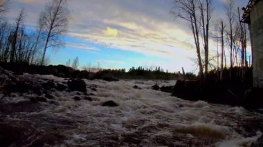 Akan suyu olan hidroelektrik baraj. Günbatımında peri şelalesi. Harika bir tatlı su şelalesi akıyor. Kükreyen bir deresi olan orman kayaları. 4K ve yavaş çekim.
