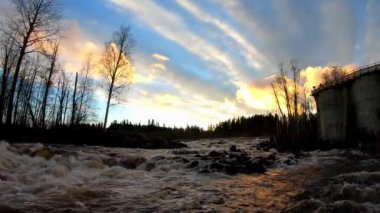 Akan suyu olan hidroelektrik baraj. Günbatımında peri şelalesi. Harika bir tatlı su şelalesi akıyor. Kükreyen bir deresi olan orman kayaları. 4K ve yavaş çekim.