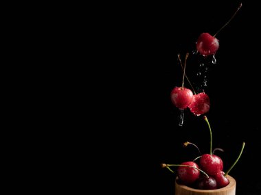 Koyu arkaplanda taze kirazlı dondurma aksiyon, sıçrama, su damlaları ve bokeh ile dinamik çekim. Yüzen taze meyve veya su damlası ve koyu arkaplan ile yükselen çekim.