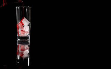 Kırmızı alkolsüz çözeltiyi buzun üstüne koyu arkaplana doğru dökmek. kopyalama alanı. İçki, şarap konsepti.