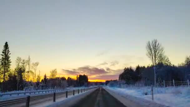 在4K时差的情况下在白雪覆盖的路上开车 清澈的天空 阳光普照在松树顶上 冬季景观下汽车驾驶的超差凸轮视图 — 图库视频影像