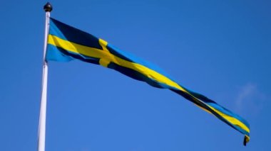 Swedish flags waving with the wind flow under the blue sky for national day celebration and symbol of european union. Swedish National day, midsummer. Slowmotion video with copyspace.