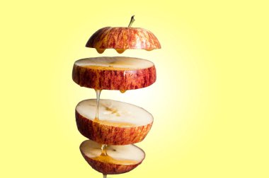 Taze dilimlenmiş kırmızı elma ve bal havada asılı duran yiyeceklere damlıyor. Alternatif şeker ikamesi, soğuk ilaç ve vücut güçlendirme, süper yiyecek kahvaltısı sarı arka plan.