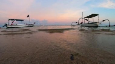 Geleneksel Balili balıkçı teknelerinin deniz kıyısına bağlı olduğu Sanur Sahili 'nde gün doğumunda. Endonezya, Bali sahilinde dramatik bulut manzarası. 4K kopyalama uzayı.