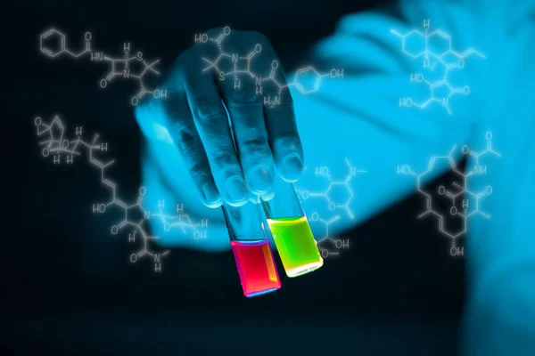 Organic sample glass vials hold by a woman scientist in a laboratory - radioactive - fluorescence. A copy space black background. Organic medicinal chemistry laboratory.