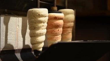 Ulusal Çek Trdelnik tatlısı 4K 'de sokakta hazırlanıyor. Taze pişmiş Trdelnik, sepetin içinde şeker ve fındık. Geleneksel Czech mutfağı. Ulusal bohem yemekleri pişirdim..