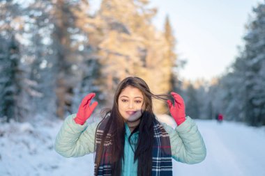  Renkli ceketli güzel bir kadının portresi. Siyah ceketli güzel bir kadın Sihirli Kış Ormanı 'nda yürüyor. Bulutlu gökyüzü ile doğal manzara. 