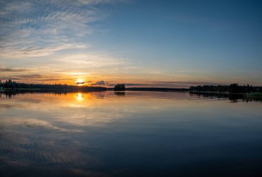Gün batımında orman gölünün üzerinde sakin bir altın saat bulutu. Dramatik bulut manzarası. Sudaki simetri yansımaları, doğal ayna. su dalgalanması gün batımı arkaplanı.