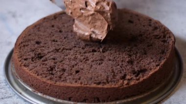 Kadın fırıncı elleri çikolatalı kek pastasını masanın üzerine çikolatalı kremayla süsler. 4K, kopyalama alanını kapat Alan derinliği.