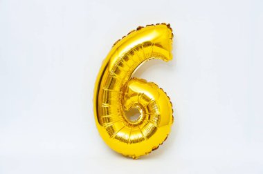 Beyaz arka planda izole edilmiş şişirilebilir numara 6 parlak metalik altın rengi. Yakın plan..