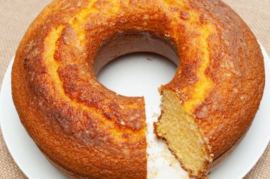 Cornmeal Cake (Bolo de Fuba) cut Brazilian style on a white plate. Isolated on jute. Top view. Close-up. Horizontal shot.