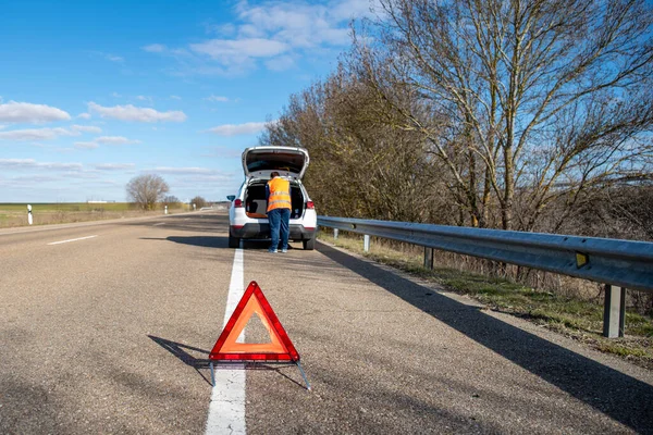 Ung Man Kollar Den Trasiga Bilen Som Står Vid Vägkanten Stockfoto