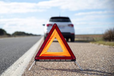Kırmızı acil durum dur işareti ve yolda kırık beyaz SUV arabası.
