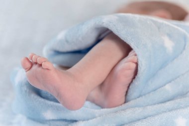 Yumuşak mavi bir battaniyenin üzerinde sevimli çocuk ayağı