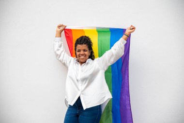 Beyaz arka planda lgtb bayrağı tutan genç bir kadın.