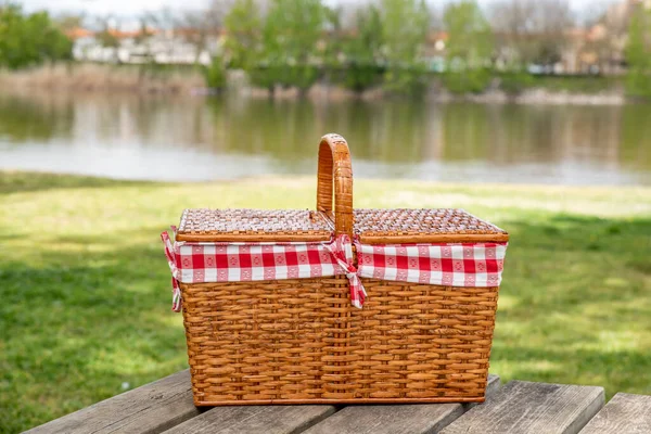 河边小树林里桌子上的野餐篮 休息和夏日心情 免版税图库图片