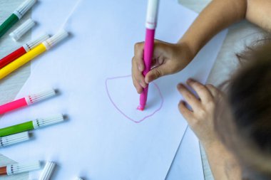 girl's hand making a drawing with colours at home