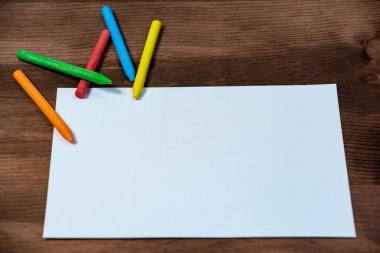 Renkli kalemler ve tahta üzerine beyaz kağıt. 