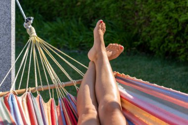 detail of the bare feet of a woman relaxing in a hammock in the garde