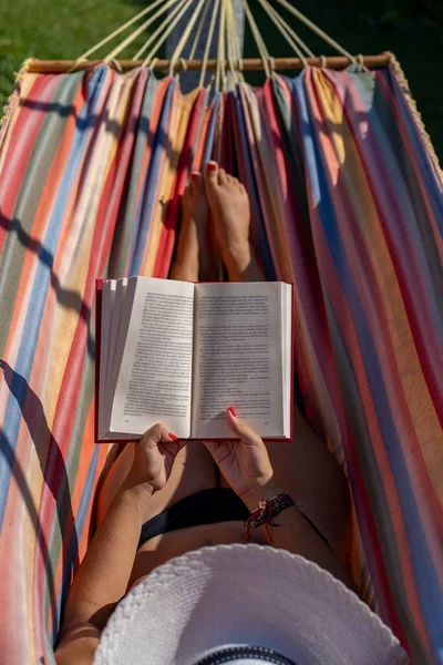 Woman White Hat Reading Relaxed Colourful Hammock Garden — Zdjęcie stockowe