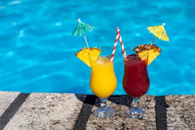 two cool cocktail glasses at the edge of the pool - tropical holiday concept