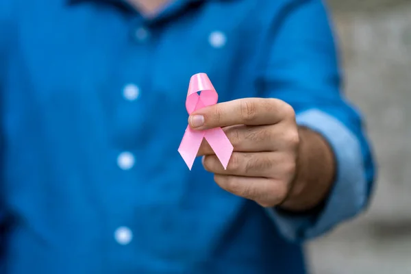 生きている人や病気を支えるピンクのリボンを持っているふりをする男乳がん意識の概念 — ストック写真