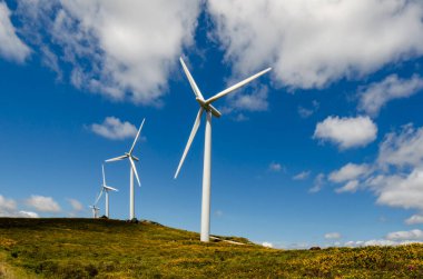 Dağlarda dört rüzgar türbini görünüyor