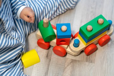 Küçük çocuk renkli ahşap bloklardan yapılmış bir trenle oynuyor.