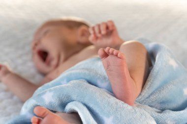 Yeni doğmuş bir bebek mavi bir battaniyenin üzerinde yatıyor.