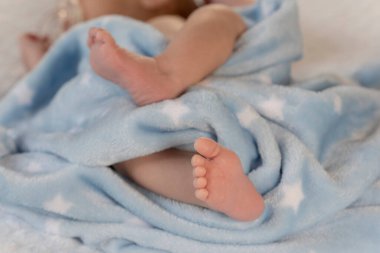 Mavi bir battaniyeye sarılı yeni doğmuş bebek ayakları.