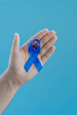 Açık mavi arka planda mavi kurdeleli genç bir adam, prostat kanseriyle mücadelenin sembolü.