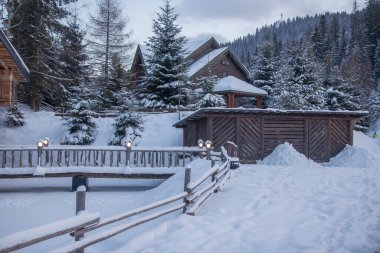 Kış dağlarına ve Noel ağaçlarına karşı köprüsü olan ahşap bir ev.