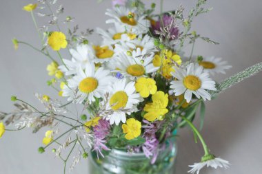 Kavanozda bir buket çiçek, masada, papatya çayı.