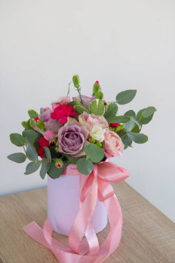Zarif bir buket çiçek, pembe bir kutuda yeşillik.