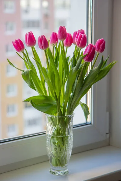 Penceredeki vazoda bir buket pembe lale.