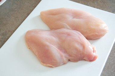 Beyaz tahtada çiğ tavuk filetosu.