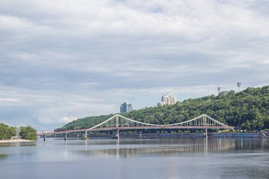 Kyiv 'deki Dinyeper Nehri' nin karşısındaki yaya köprüsünde insanlar nehrin kıyısında dinleniyor.