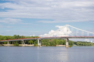 Kyiv 'deki Dinyeper Nehri' nin karşısındaki yaya köprüsünde insanlar nehrin kıyısında dinleniyor.