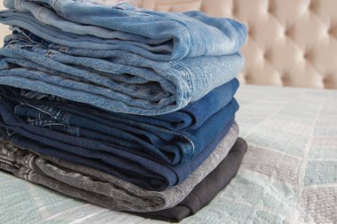 Yatağın üzerinde kot pantolon yığını