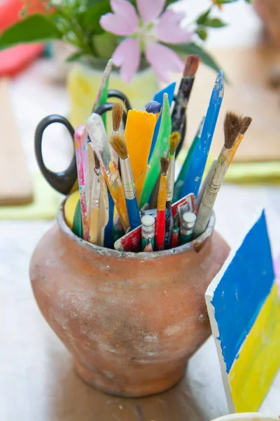 brushes and pencils in a clay pot, flag of ukraine