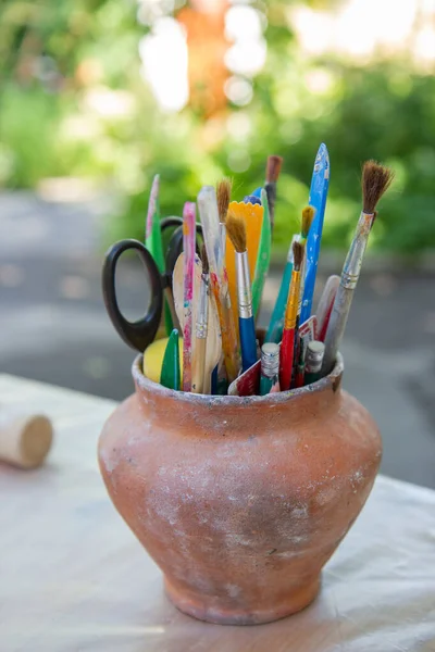 brushes and pencils in a clay pot