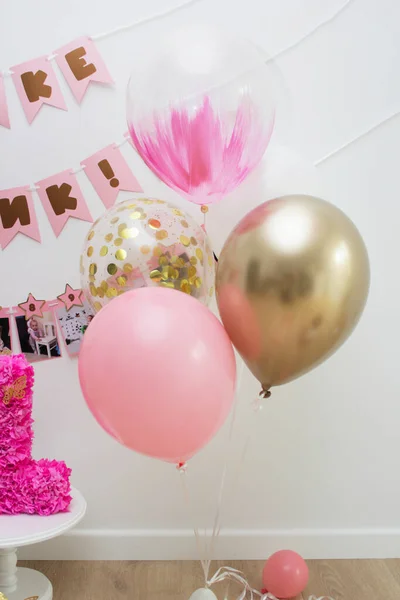 Pink photo zone with balloons, garlands and a number for 1 year