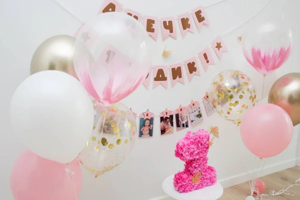 Pink photo zone with balloons, garlands and a number for 1 year