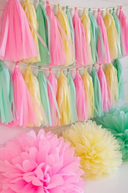 Tatil için püsküllü kağıt çelenkler ve ponponlar. Pembe, nane ve sarı çelenkler ve ponponlar.