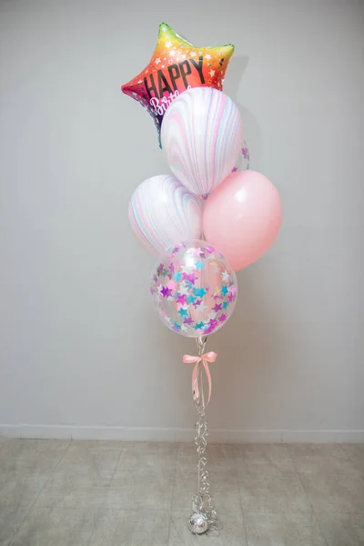 A set of balloons with helium. Striped balloons and balloons with confetti. Multi-colored star balloon with the inscription \