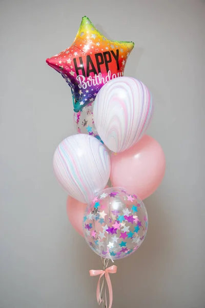 A set of balloons with helium. Striped balloons and balloons with confetti. Multi-colored star balloon with the inscription \