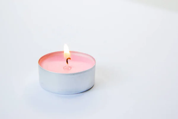 burning pink candle on a pink background