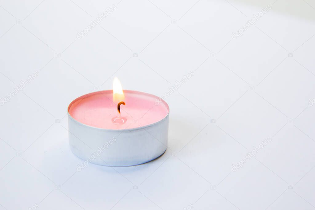 burning pink candle on a pink background