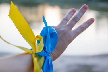 blue-yellow ribbons on the hands, the flag and the trident of Ukraine